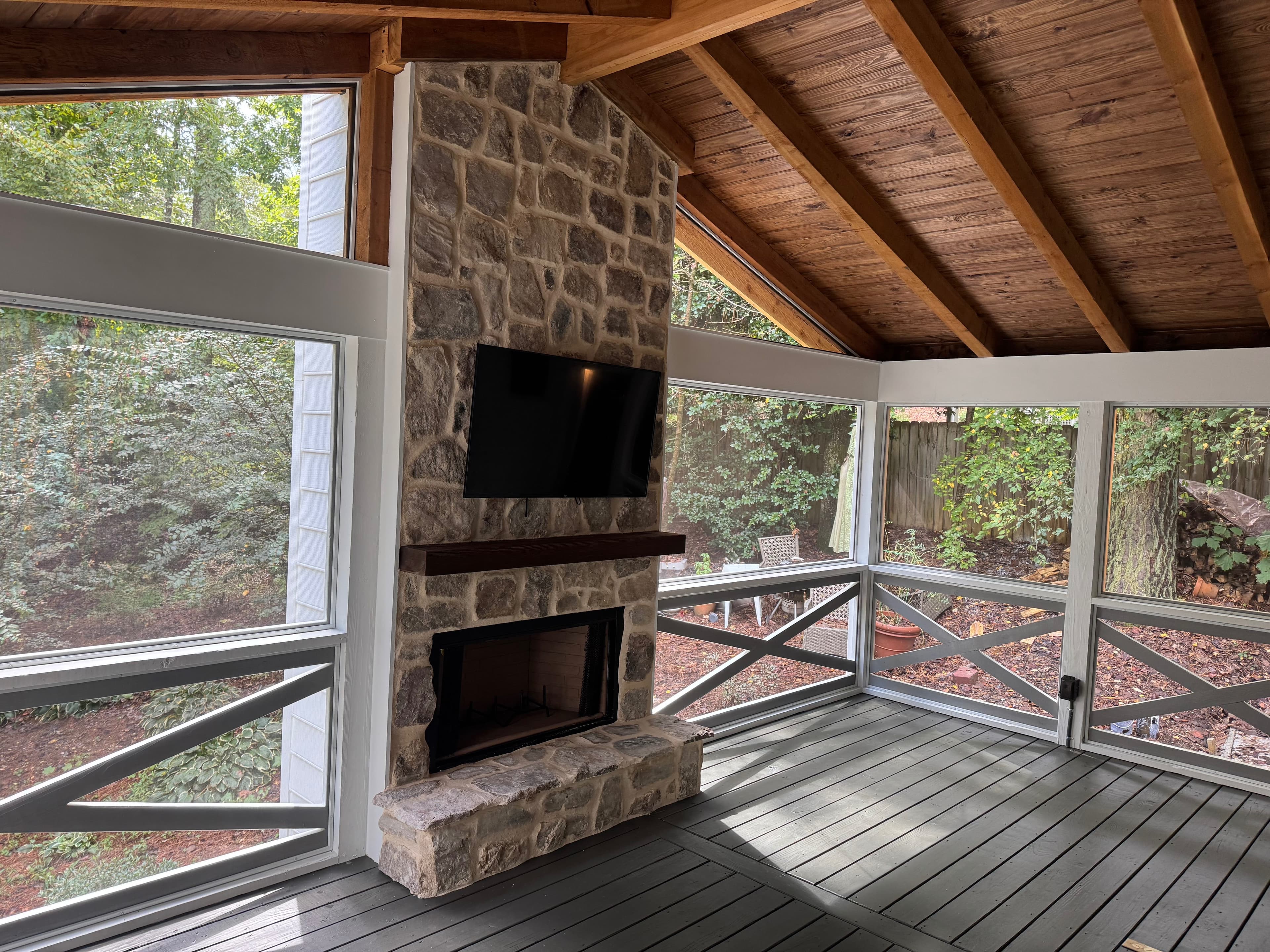 Screened porch interior with stone fireplace and vaulted ceiling