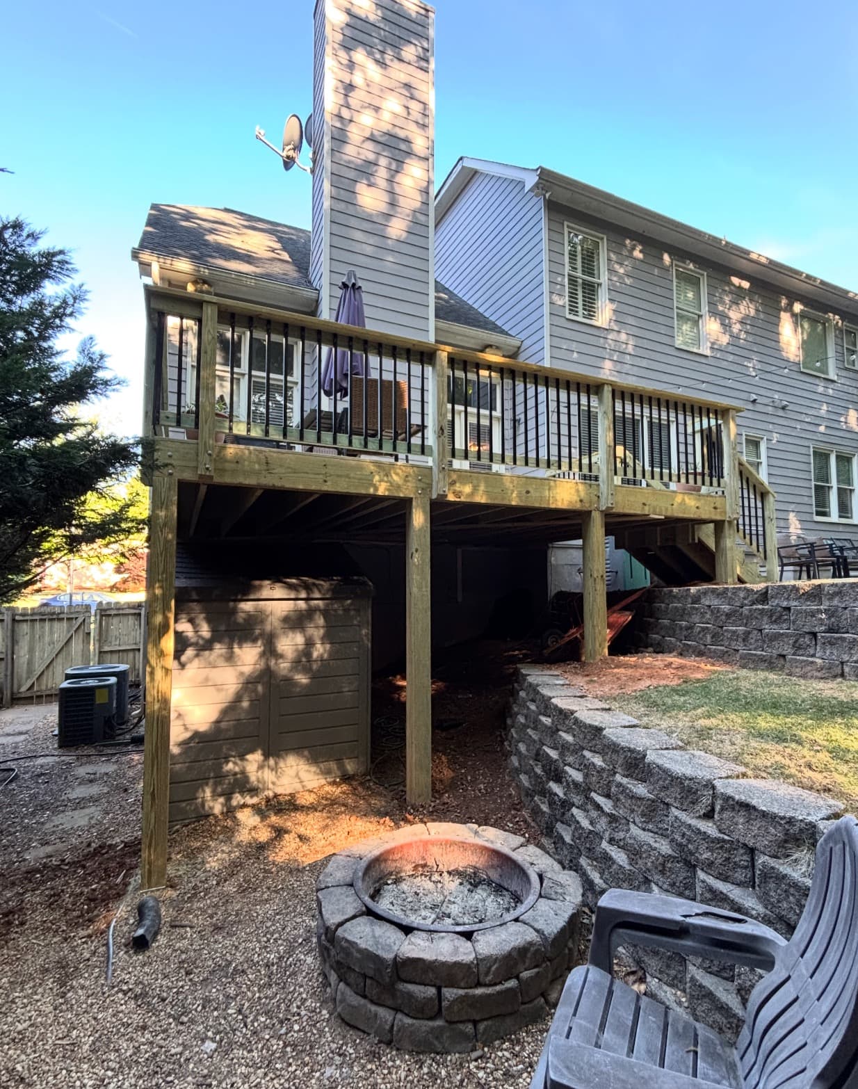 Elevated deck with stone retaining wall and fire pit below