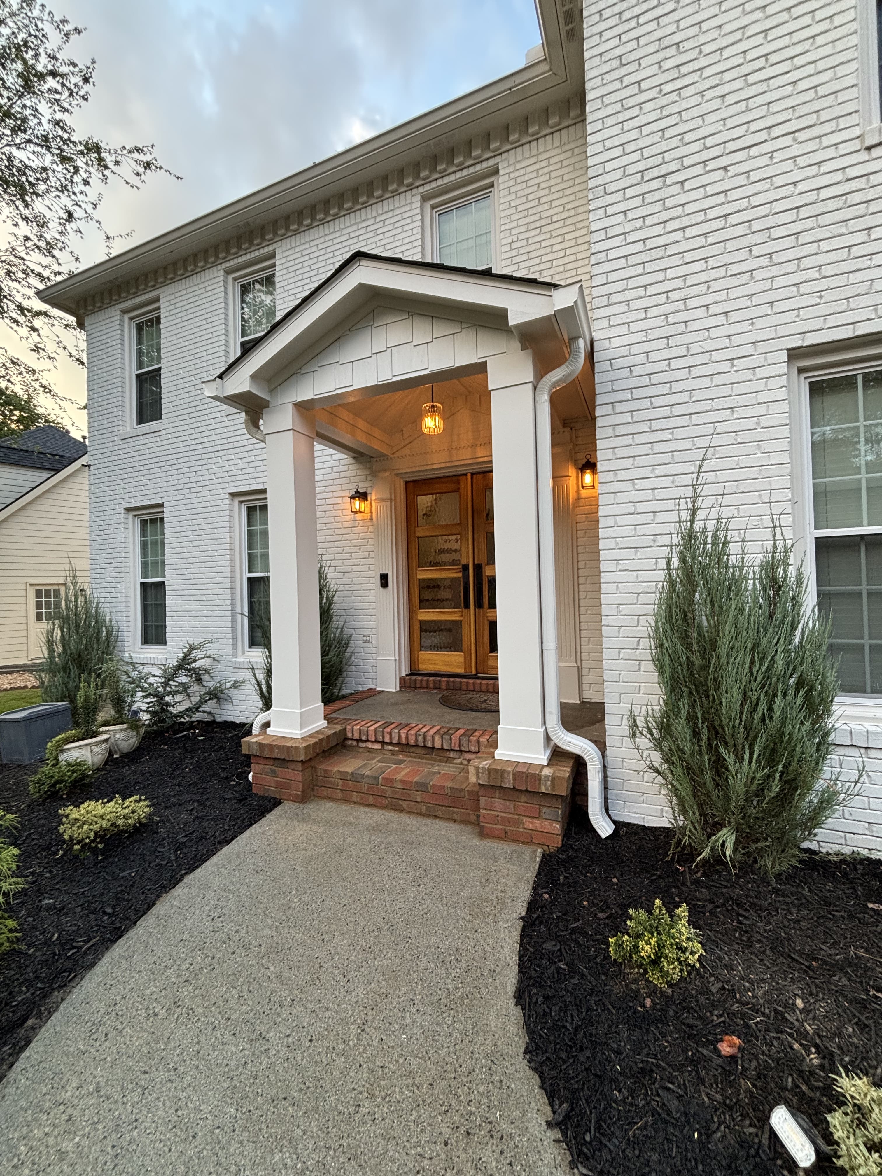 White painted brick home with gabled portico entry