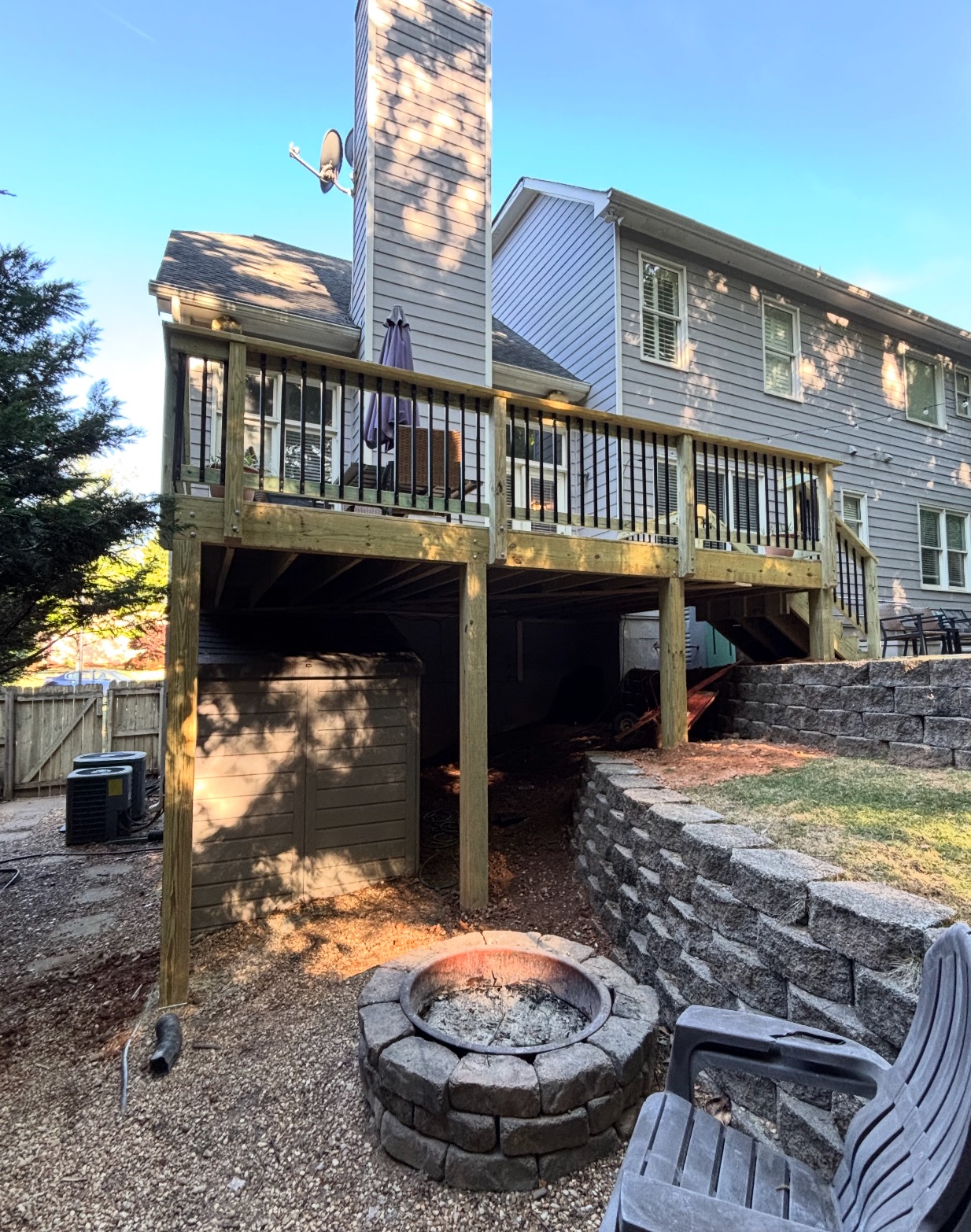 Elevated deck with stone retaining wall and fire pit below