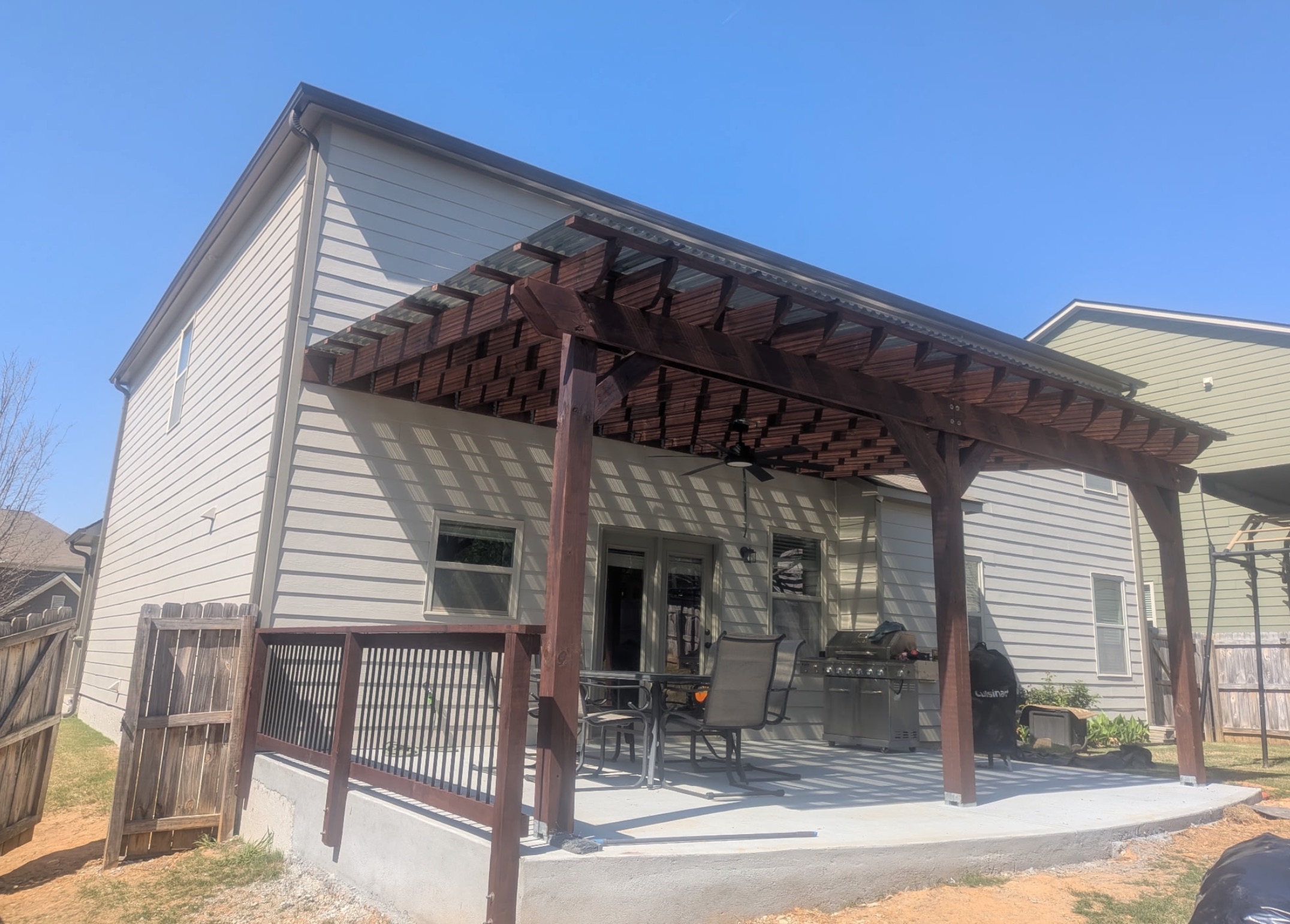 Dark stained cedar pergola over concrete patio with grilling area