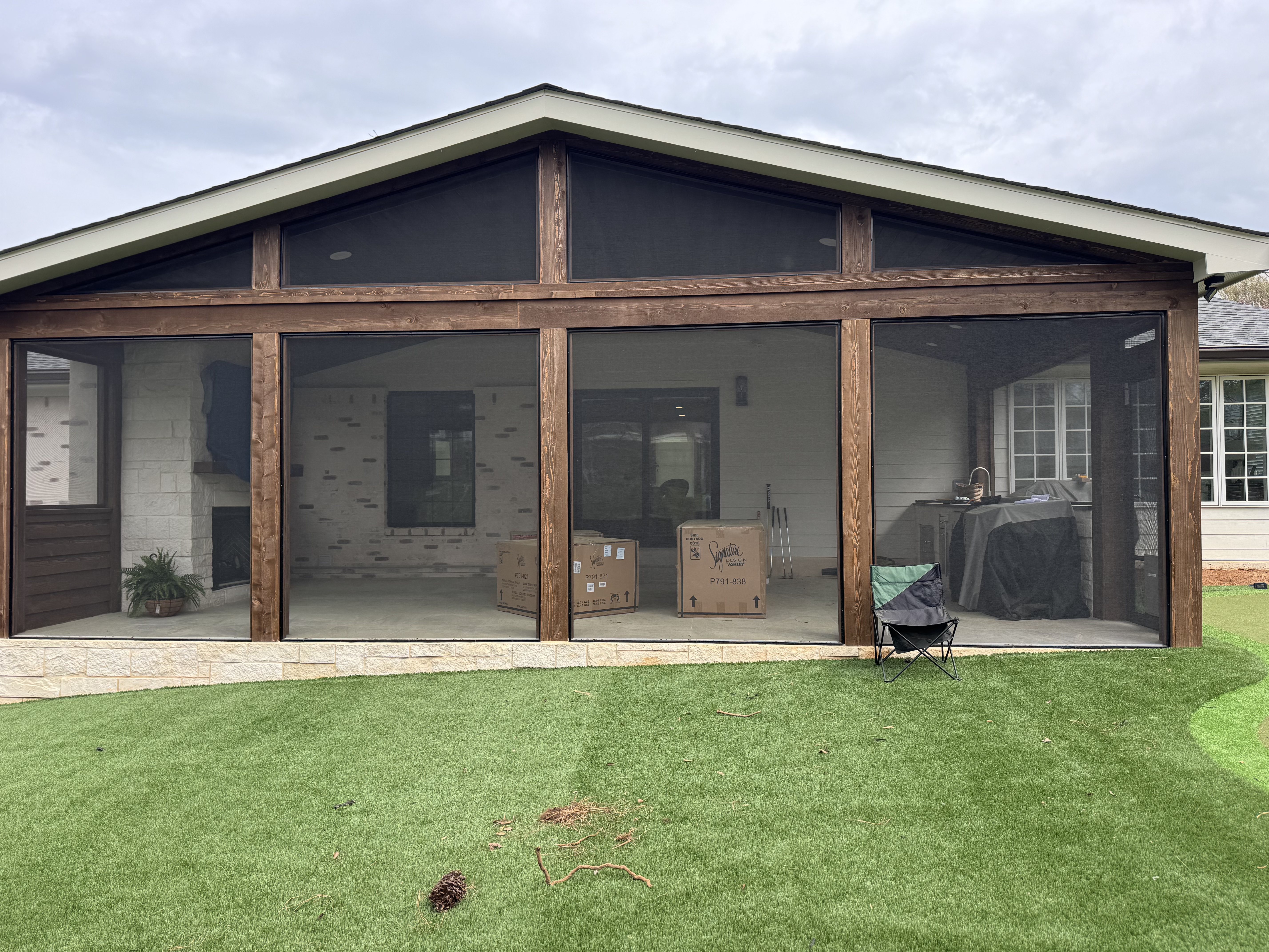 Large gabled screened porch with stained wood beams and stone base