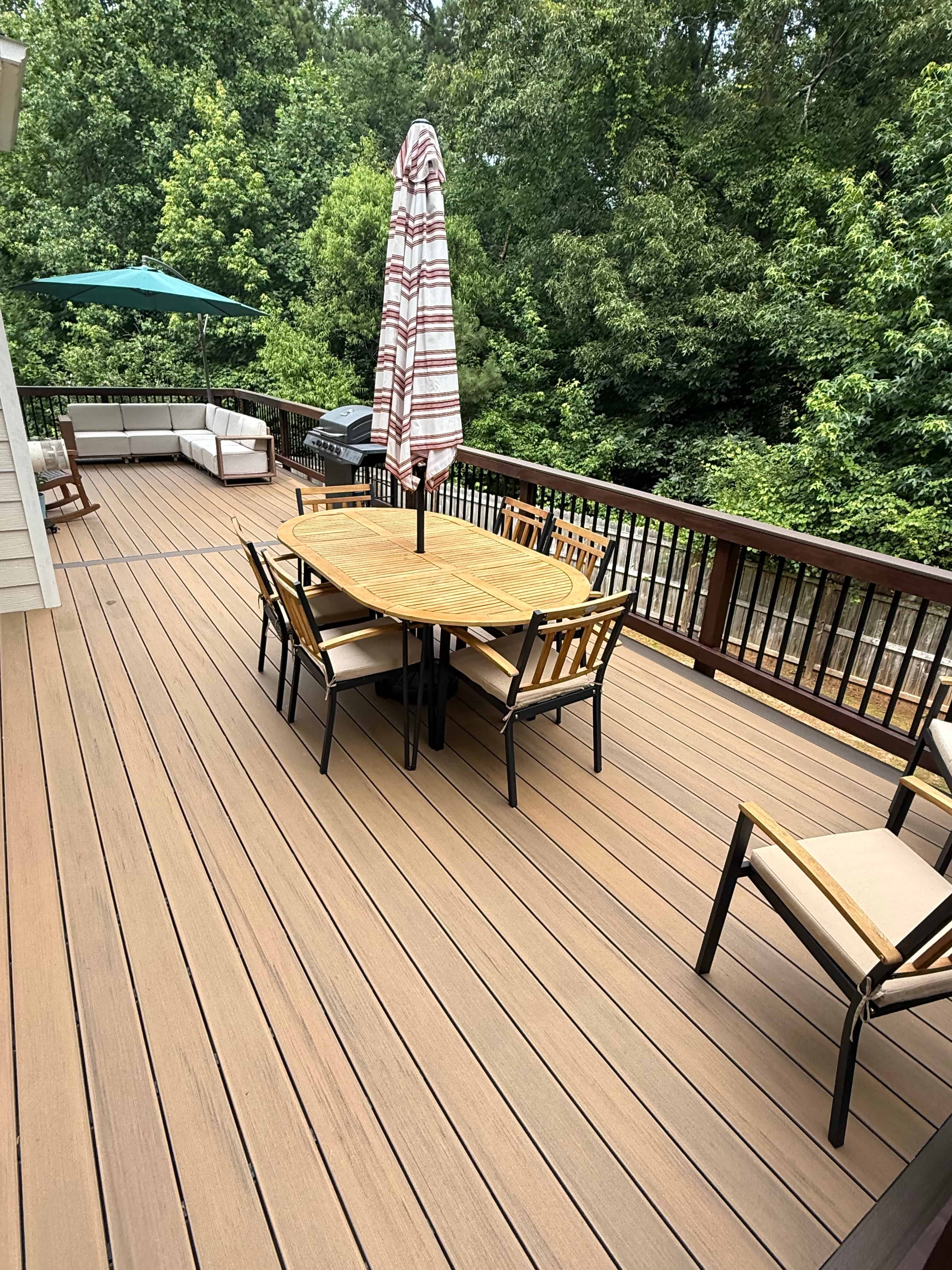 Two-tone composite deck with teak dining set, sectional sofa, and black metal railings