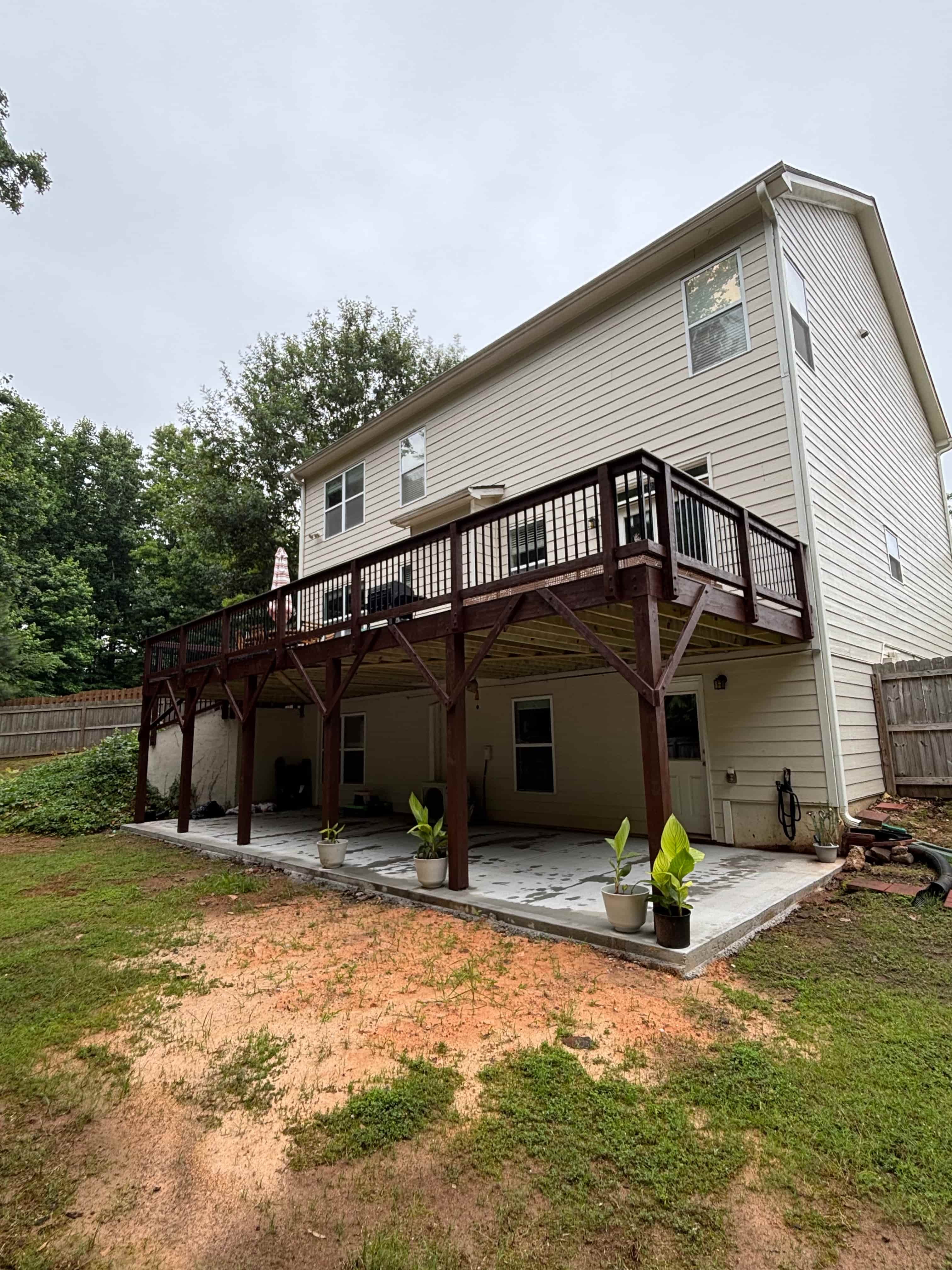 Rear view of elevated dark-stained deck with landscaped concrete patio