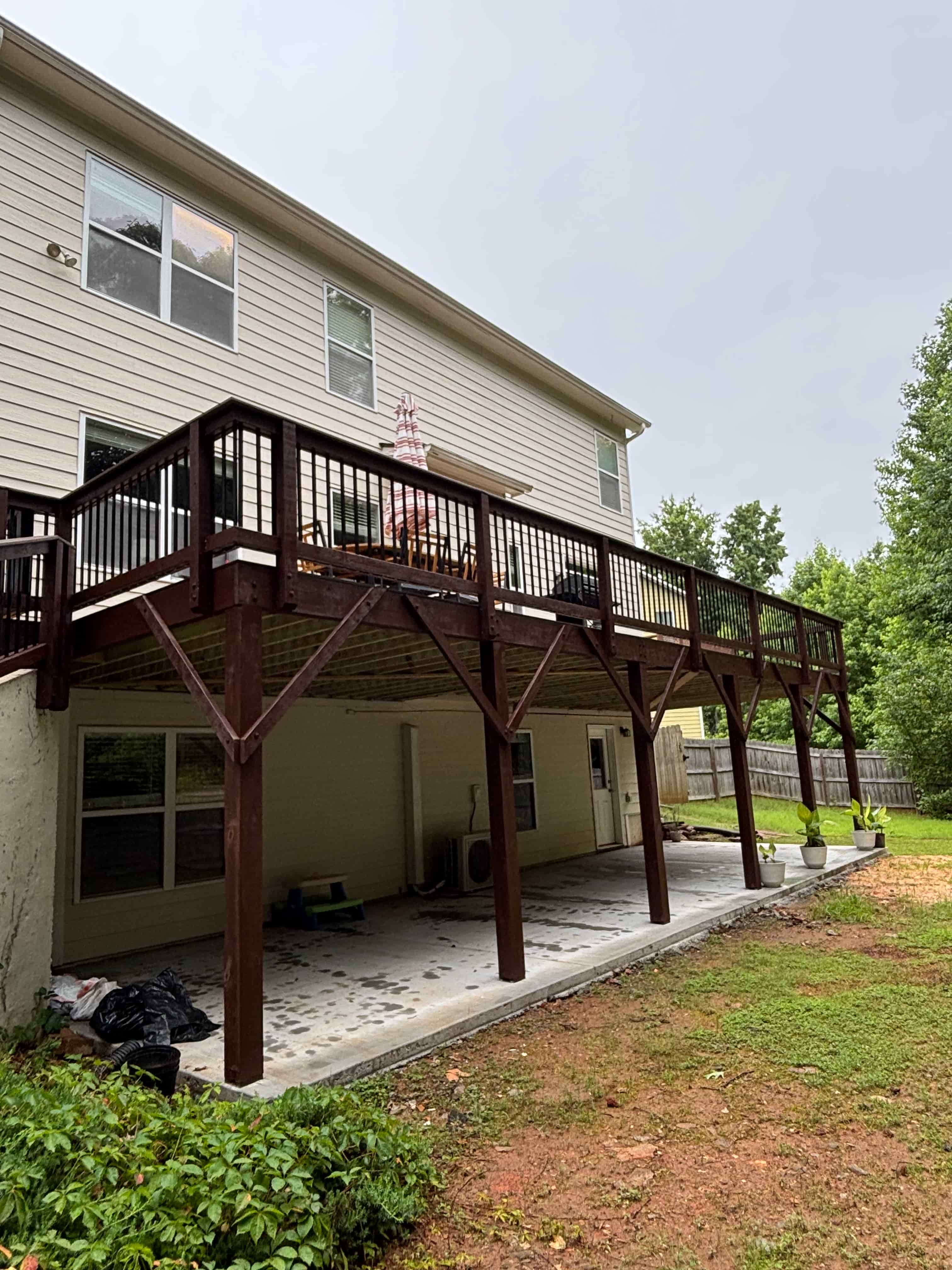 Side profile of elevated deck with dark-stained wood supports and under-deck patio