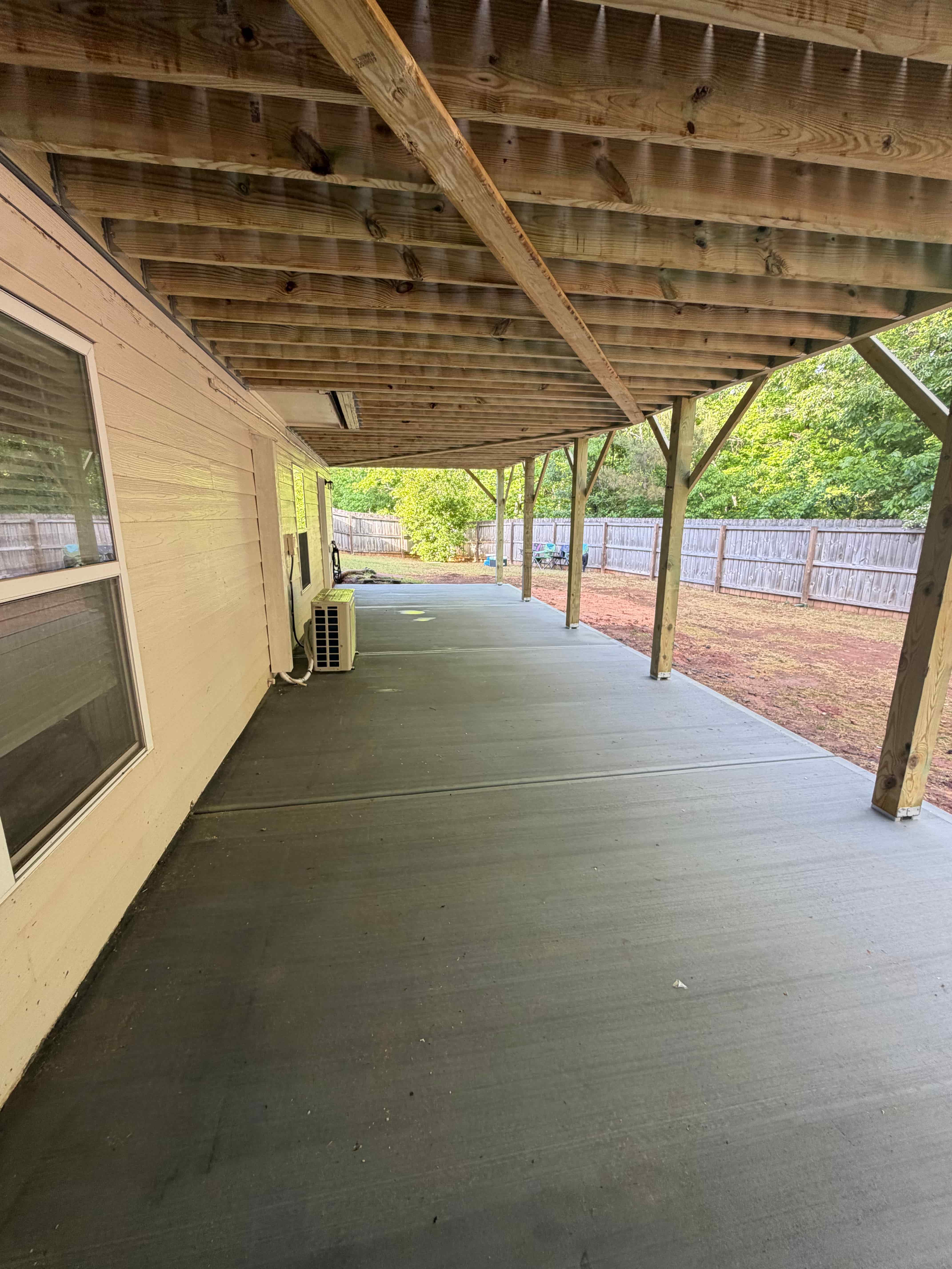 Under-deck concrete patio with exposed wood framing ceiling